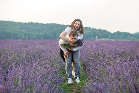 Beautiful happy couple, walking in purple lavender field, having fun in flower meadow. romantic date and loveの写真素材