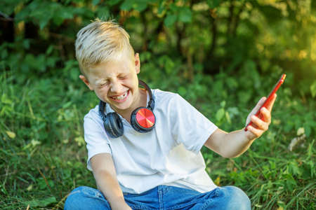 Boy communicates via video chat using smart phone and Internet. Child laughs emotionally. Technology...