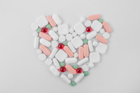 Many different pills on white background, laid out in form of heart. Copy space. Top view. Concept of pharmaceuticals, medicine and healthcareの写真素材