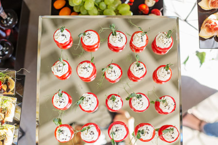 catering buffet table with snacks and appetizers. Stuffed cherry tomatoes with cheese.