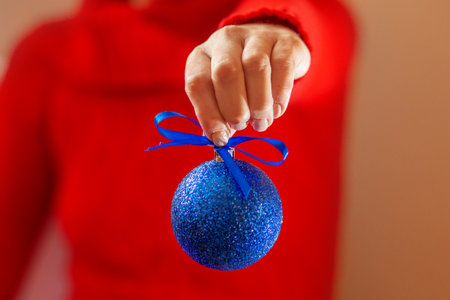 Christmas tree ball in hand on red background. Copy spaceの写真素材
