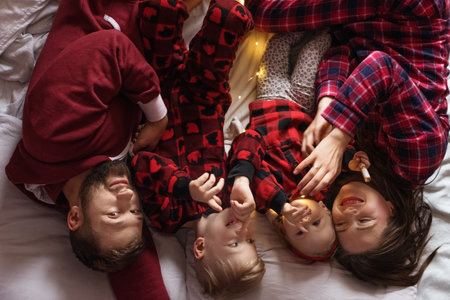 Family is lying on bed and having fun. Parents and son and daughter. Flat lay.の写真素材