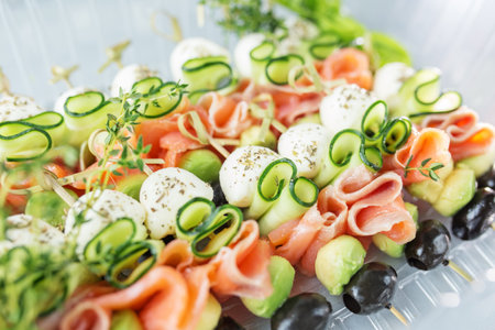 Appetizers with red fish, avocado, mozzarella and cucumbers close-up. Food and catering concept.の写真素材