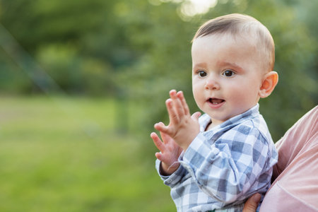 Portrait of happy baby that mother is holding in her arms outdoors. Little toddler son.の写真素材