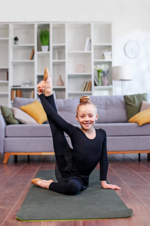 Little girl practicing stretching in room. Physical exercises for children at home. Concept of sports and healthy lifestyle.の写真素材
