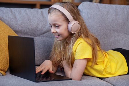 Child studying online using laptop and headphones. Childhood and entertainment concept.