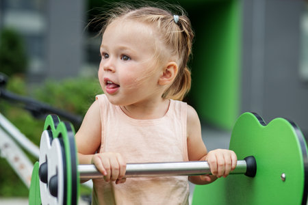 Rocking frog with spring for kids. Little toddler girl having fun at playground. Concept of kindergarten, baby development and early yearsの写真素材