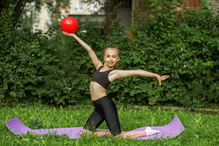Girl gymnast performs an exercise with ball on sport mat. Rhythmic gymnastics. Healthcare conceptの写真素材