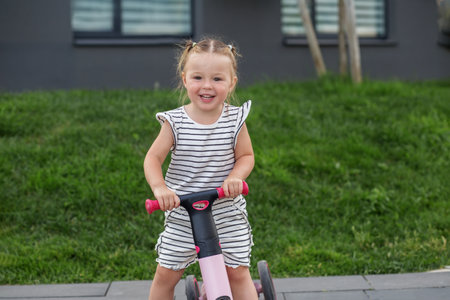 Toddler girl driving balance bike outdoors. Learning to ride bike concept. Urban.の写真素材