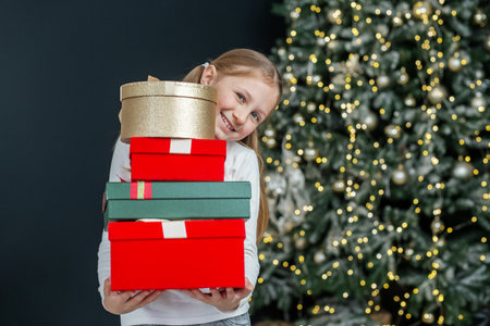 Preteen child with gift boxes in room. Concept New Year, Merry Christmas, holiday, vacation, winter,...