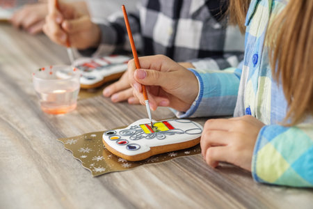 Children draws food paints on Christmas homemade gingerbread cookies. Christmas concept. Close up....