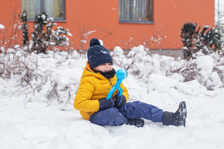 Small boy have fun making snowballs with toy plastic maker. Kid playing snowballs. Winter games outdoors.の写真素材