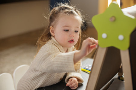 Early brain development. Toddler girl draws on blackboard at home.の写真素材