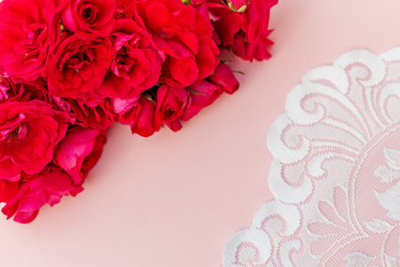 Cluster of deep pink roses paired with elegant white lace detail on a soft blush background, ideal for romantic or vintage themes.の写真素材