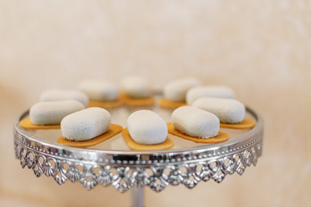 Minimalist white dessert bites arranged on decorative silver stand, served as elegant sweet treats at luxury celebration or wedding.の写真素材