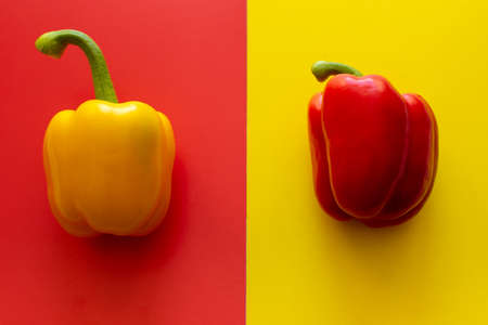 Yellow pepper on a red background and red pepper on a yellow background top viewの写真素材