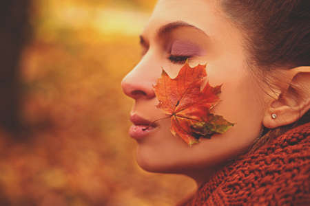 The face of a girl with her eyes closed with a leaf on her cheekの写真素材