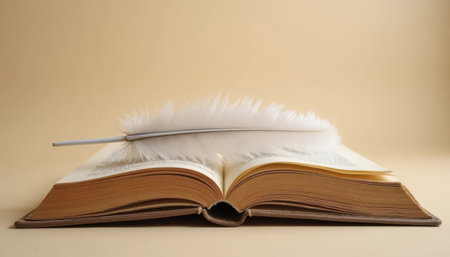Close-up of a feather resting on an old book against a beige background, symbolizing wisdom, literature, history, and creativity. Perfect for Book Day.の素材