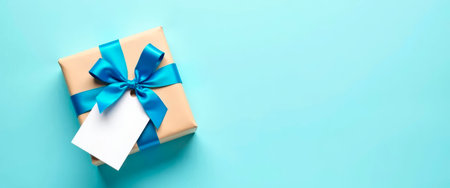 Gift box with blue ribbon and blank tag on pastel background. Ideal for celebration, giving, or festive design.の素材
