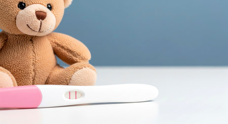 Positive pregnancy test with a teddy bear. New baby arrival, maternity, and family happiness.の素材