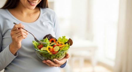 Pregnant woman eating fresh vegetable salad. Healthy nutrition concept for prenatal care and balanced lifestyle.の素材
