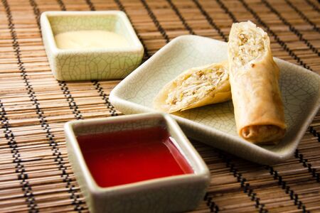 Eggroll, yellow and red sauce on a bamboo matの写真素材