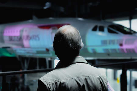 Old man from behind, admiring the Concorde passenger plane at Filton air museum, Bristol, UK.
