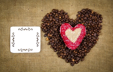 Heart of coffee beans on the sackcloth
 background with the place for the sample textの写真素材