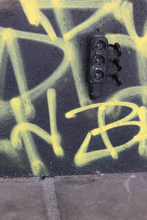 Black socket on the black wall painted with yellow graffiti. Street style. Urban Lonelyness. Connection Caligraphy. Letters. Art concept.の写真素材