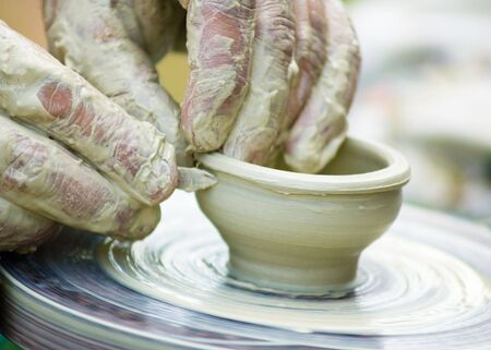 Potters hands creating a clay masterpiece at the turning wheel.の写真素材