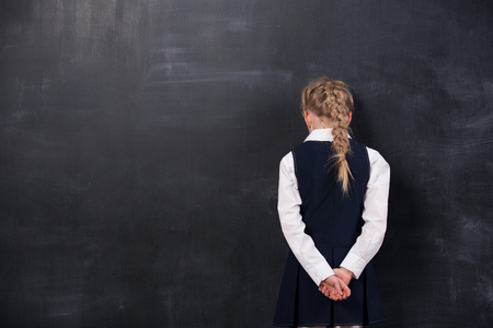Portrait of schoolgirl leaning her forehead against blackboardの写真素材