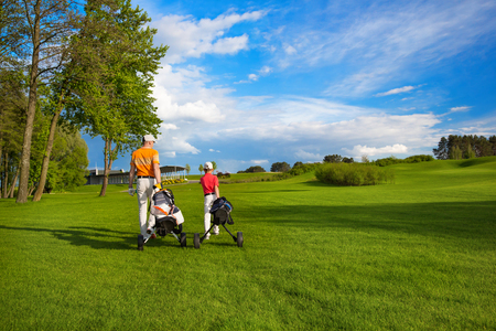 Father with son are walking at golf fieldの写真素材
