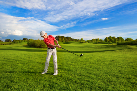 Boy golf player hitting by iron from fairwayの写真素材