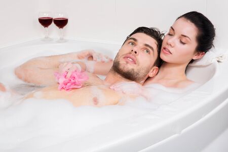 young beautiful couple is taking a bubble bathの写真素材