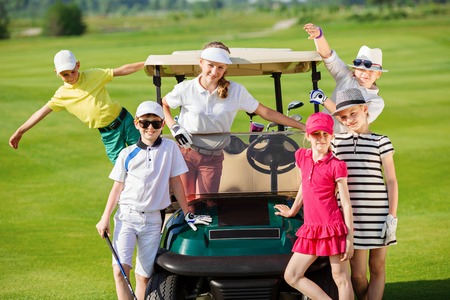 Children posing near golf car at golf course at summer dayの写真素材