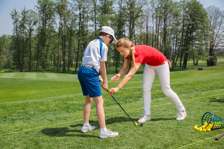Kids practicing with trainer at golf school at summer dayの写真素材