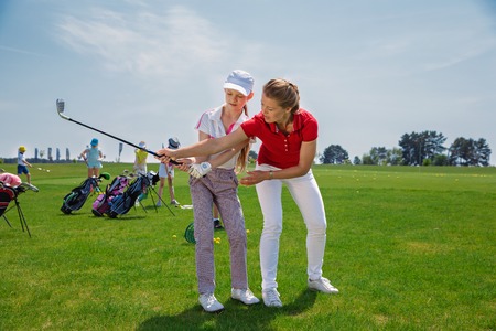 Kids practicing with trainer at golf school at summer dayの写真素材