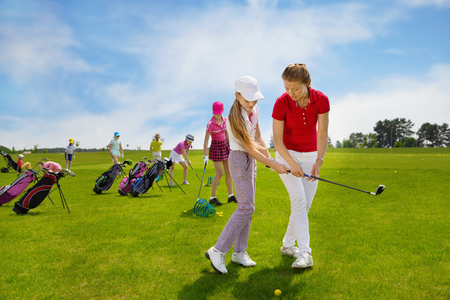 Kids practicing hits with trainer at golf school at summer dayの写真素材