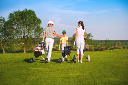 Family golfers plaing golf at sunny day, back viewの写真素材