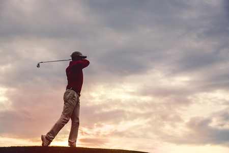 silhouette of man golfer with golf club at sunsetの写真素材