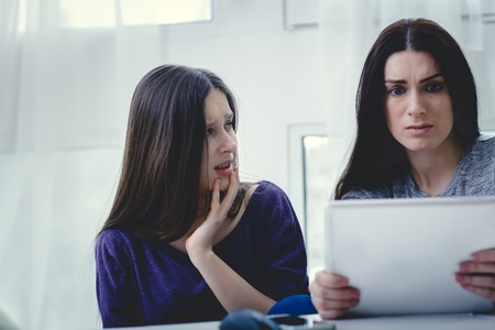 Scared mother arguing daughter over online activity. Cyber bullying or blue whale game conceptの写真素材