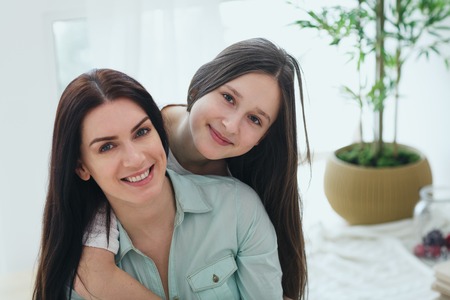 Beautiful mother and her cute daughter smiling and posing at home.の写真素材