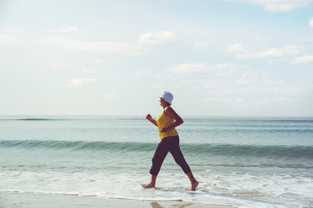 senior woman jogging on sea beachの写真素材