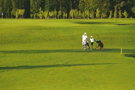 man with his son golfers walking on golf courseの写真素材