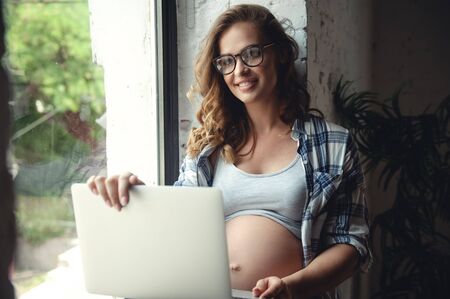 Pregnant woman use of laptop computer for working at homeの写真素材