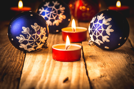 Blue and red christmas balls and lit red candles on wood background toned greeting card templateの写真素材
