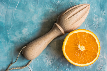 Juicy ripe fresh orange cut in half with wooden reamer on blue background, flatlayの写真素材