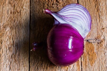 Peeled purple onion cut in half on weathered wood kitchen table. Healthy food ingredients vitamins conceptの写真素材