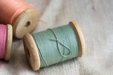 Vintage wooden thread spools on linen cloth, pastel colors, closeup, styled image for social media, blogging, copyspaceの写真素材