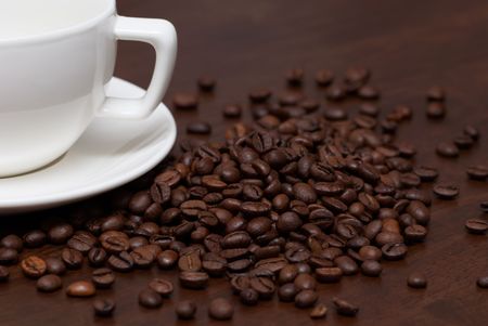 Coffee beans and cup on a brown wooden tableの写真素材